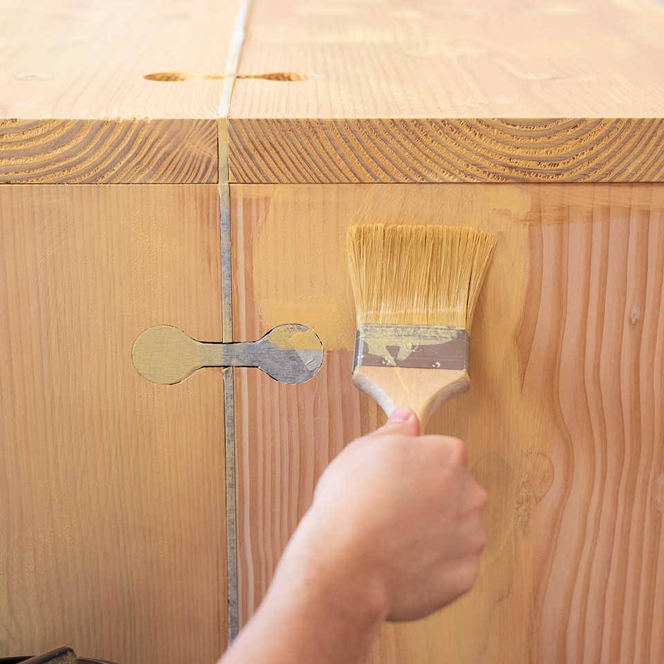 Auftragen von Hybrid-Holzschutz auf einen Holztisch zum UV-Schutz.